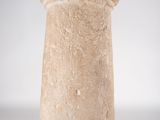 an old stone vase on a metal stand on a white surface