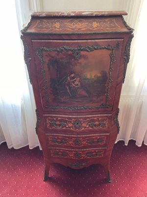 a wooden cabinet with a painting on it in the corner of a room