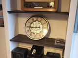 une étagère sur laquelle se trouvent une horloge, des haut-parleurs et une radio