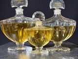 three glass bottles of perfume sitting on top of a marble counter
