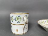 a white cup with a bird on it next to a bowl