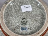 a vase with a cracky surface and a tag on it
