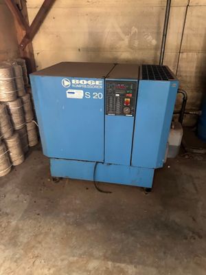 a blue machine sitting in a garage next to stacks of metal