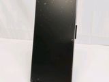 the back of a black cell phone sitting on top of a white table