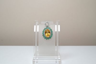 un collier jaune et vert présenté dans une vitrine transparente