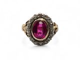 a close up of a ring with a pink stone surrounded by black diamonds