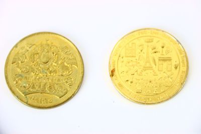 deux pièces d'or posées l'une à côté de l'autre sur une surface blanche