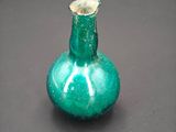 a green glass vase with a gold top on a table