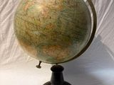 an old globe is sitting on a stand on a white surface