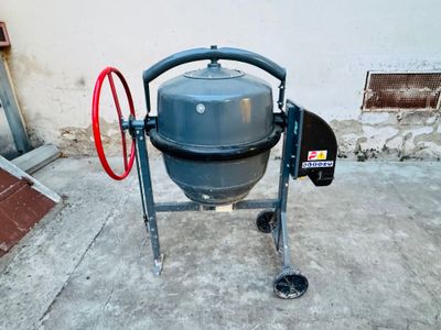 a cement mixer sitting on the concrete outside of a building