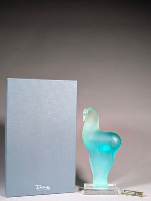 une sculpture en verre bleu représentant un oiseau, à côté d'une boîte bleue