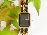 a black and gold watch sitting on a gold chain