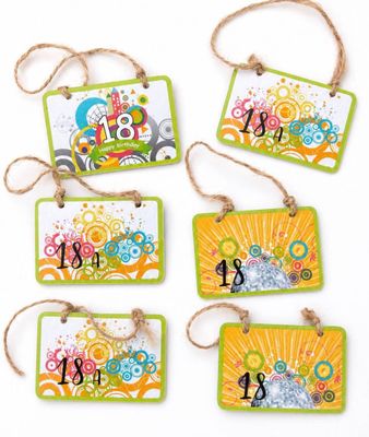four tags with different designs hanging from strings on a white surface