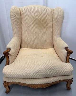 La chaise est en bois et son assise est rembourrée de couleur beige.