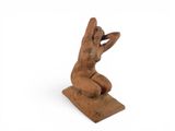 an old wooden statue of a woman sitting on a block