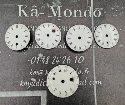 cinq horloges accrochées au mur d'un immeuble sur lequel est accrochée une enseigne
