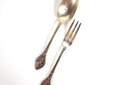 two silver spoons and a fork on a white surface