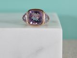 a close up of a ring with a purple stone on a marble block