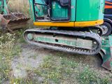a green and yellow excavator that is sitting in the grass