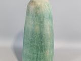un vase vert posé sur une table blanche