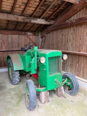 un tracteur vert garé dans une grange aux murs en bois