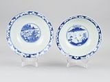 pair of blue and white plates with a landscape scene on them