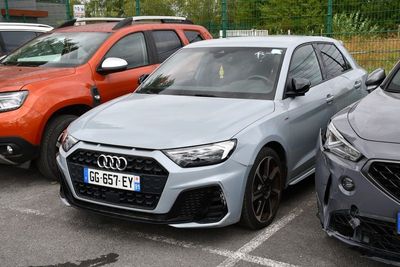 Plusieurs voitures sont garées sur un parking près d'une clôture.