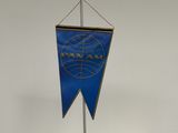 un drapeau bleu et or sur un mât, posé sur une surface blanche