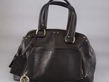a black leather handbag with gold hardware on a grey background