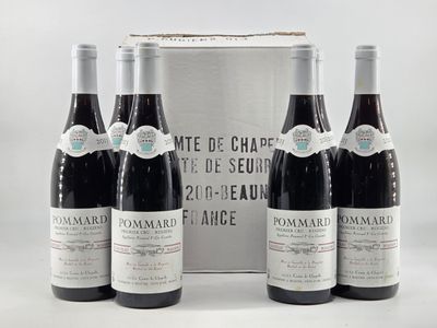 three bottles of red wine sit in front of a silver box