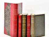 several old books are stacked on top of each other on a white surface