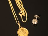 a close up of a gold necklace and earring on a black surface