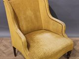 une chaise jaune posée sur un parquet, près d'un mur gris
