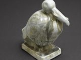 statue of a pelican sitting on a base on a gray surface