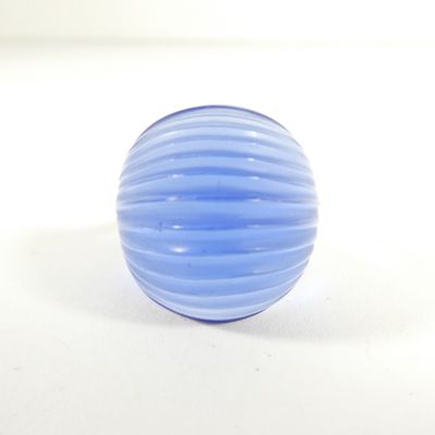 une boule de verre bleue posée sur une surface blanche