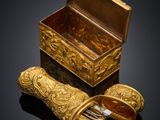an image of a gold box and a pair of shoes on a black surface