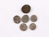 six silver coins and one silver coin on a white surface