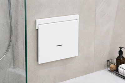 une porte de douche en verre dans une salle de bains équipée d'un distributeur de savon fixé au mur