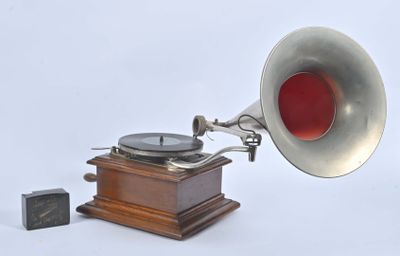 un gramophone argenté et rouge posé à côté d'un bloc de bois