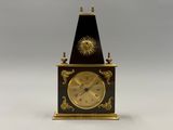 l'image d'une petite horloge surmontée d'un soleil