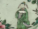 a plate with a painting of a man holding a book
