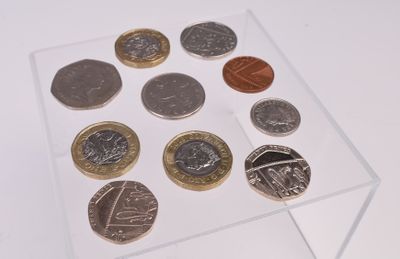 une vitrine transparente contenant des pièces de monnaie, posée sur une surface blanche