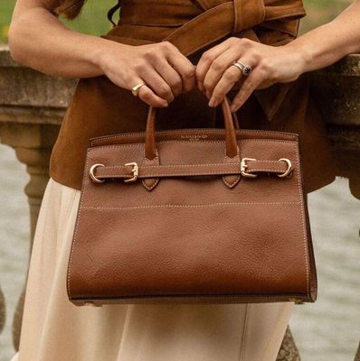 une femme qui tient un sac marron à la main