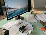 a computer monitor sitting on top of a desk covered in papers