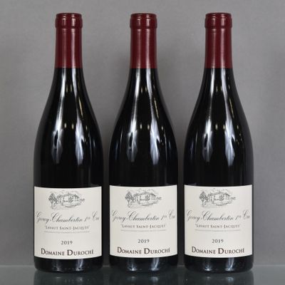 three bottles of red wine are lined up on a table