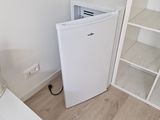 un petit réfrigérateur blanc dans le coin d'une pièce