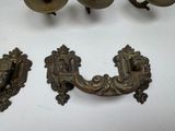 three antique brass door handles on a white surface
