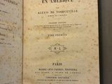 un livre ouvert posé sur une table, avec une feuille de papier dessus