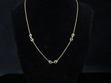 a gold necklace on a mannequin display with a black background
