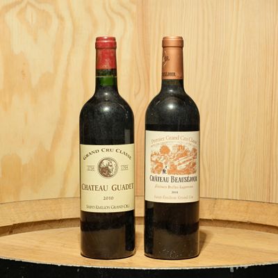 two bottles of wine sitting on top of a barrel